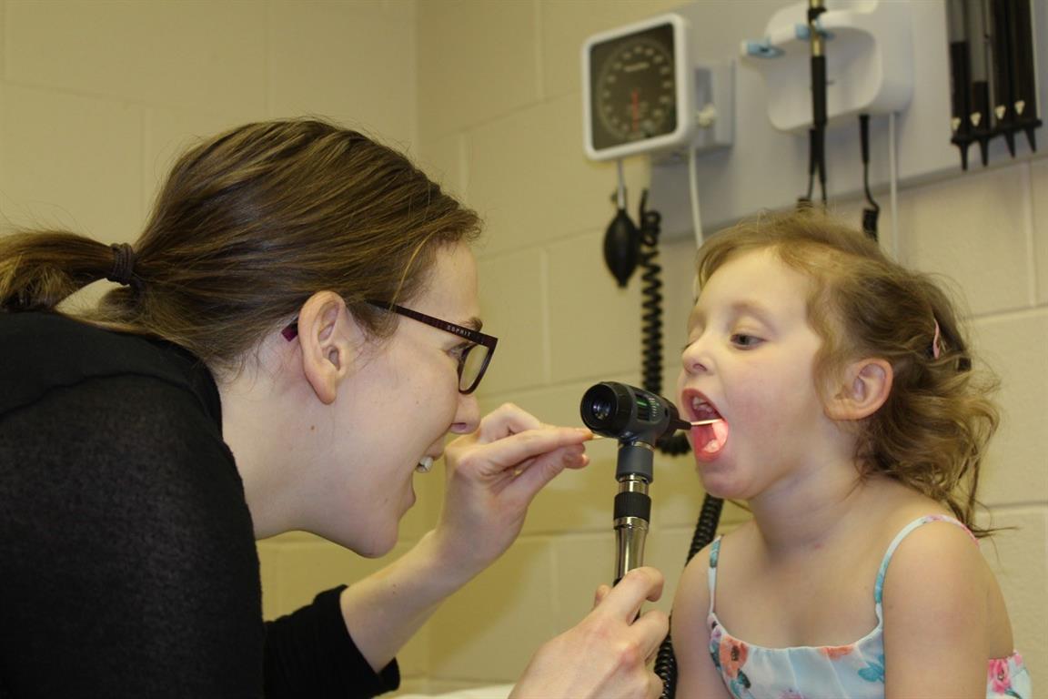 Nurse looking into the mouth of a young patient