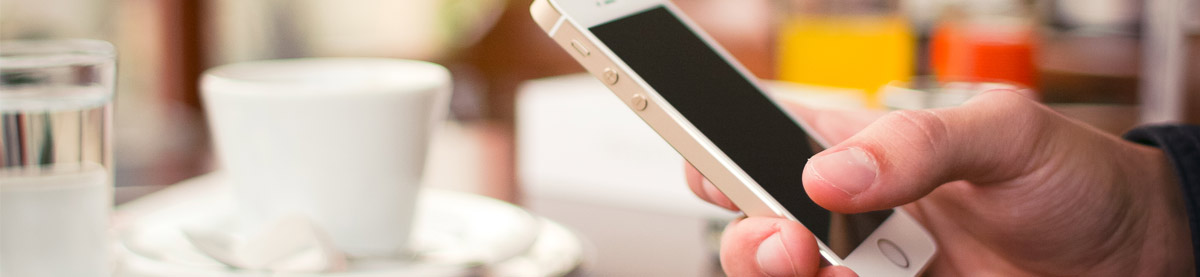 Close up of man's hand holding a smartphone in a coffee shop