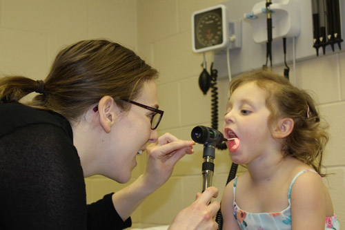 Doctor examining young girl's throat