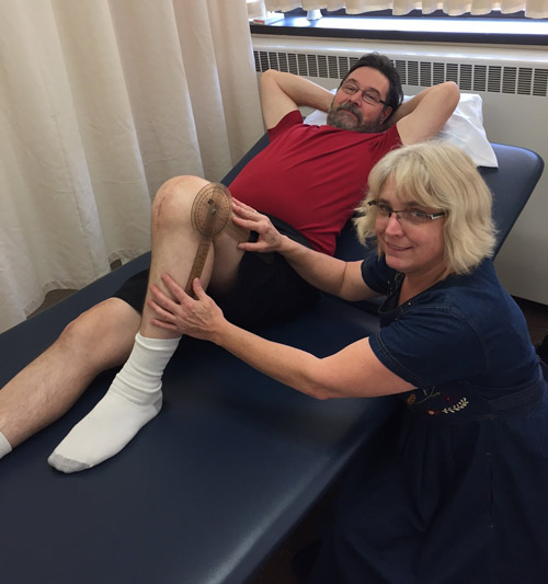 Patient lying down with bent knee with physiotherapist